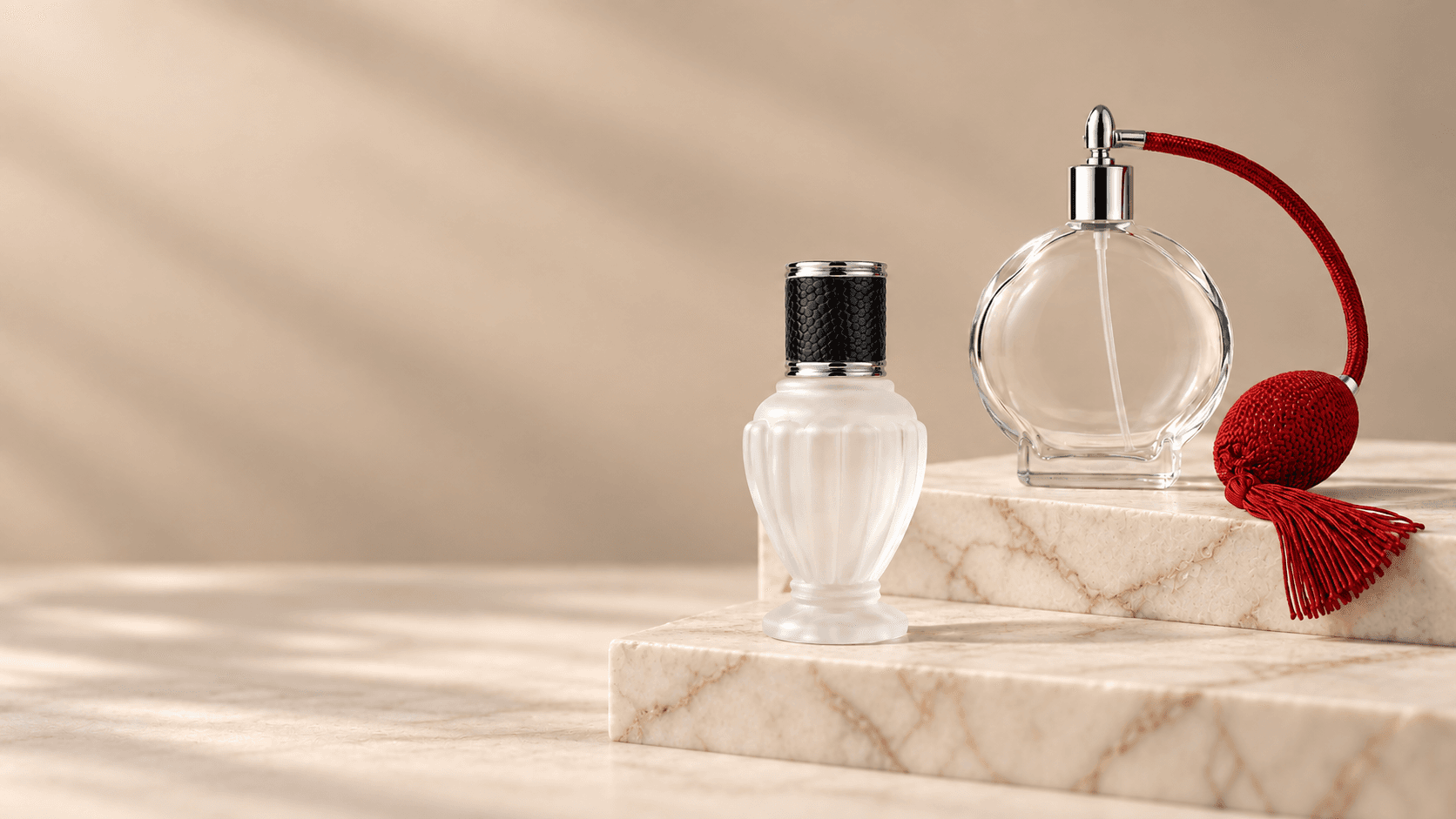 Frosted Diva bottle with a black leather-textured cap on a lower ivory marble step, beside a clear Circle bottle with a red vintage bulb and tassel